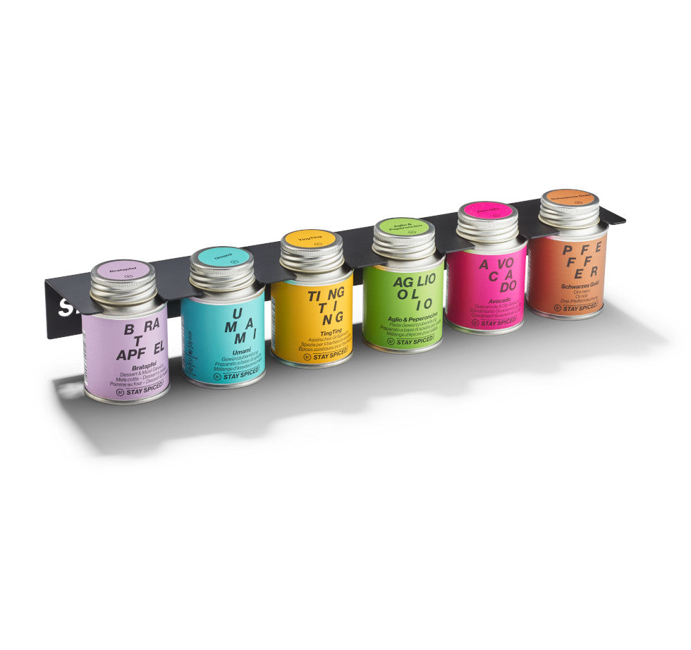 Schwarzes Hänge-Regal aus Edelstahl bestückt mit sechs bunten STAY SPICED! Gewürzdosen für die Küchenwand