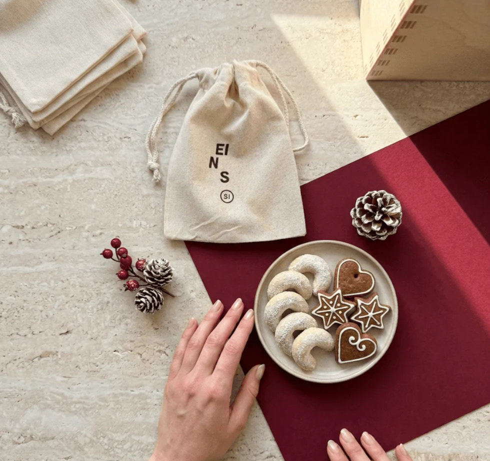 Das erste Jutesaeckchen des leeren STAY SPICED! DIY Adventskalenders neben festlicher Dekoration und Weihnachtsgebaeck