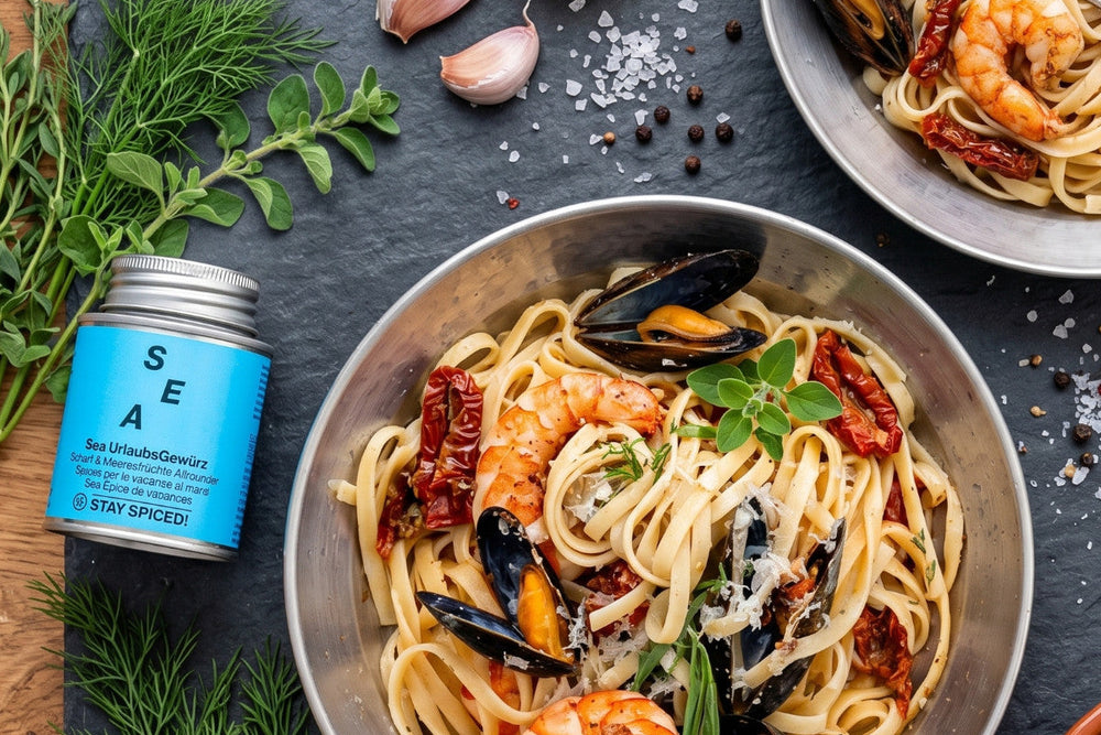Tagliatelle del Mare mit Garnelen, Miesmuscheln, getrockneten Tomaten, Parmesan und Kräutern liegt in einer Pfanne