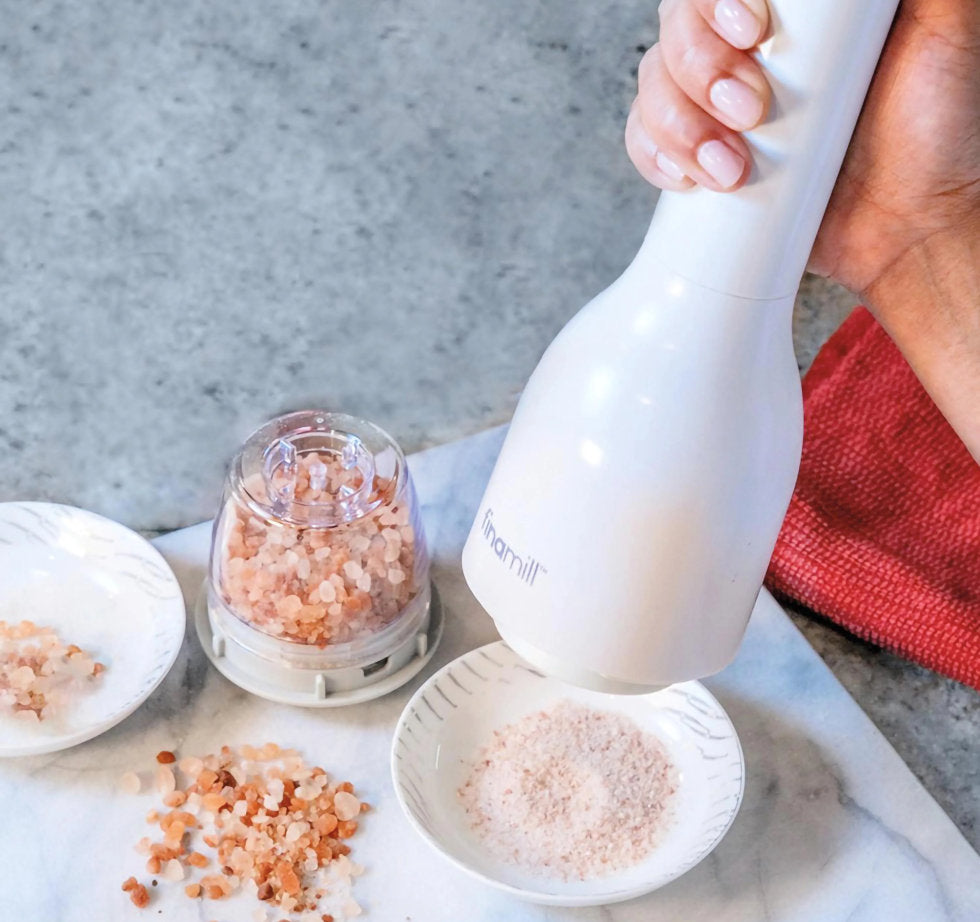 Einhandbedienung der elektrischen FinaMill Salzmühle in Soft-cream beim frischen Mahlen von rosa Kristallsalz