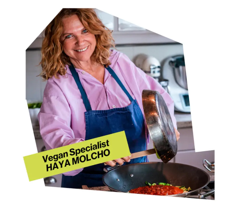 Vegan Specialist und Köchin Haya Molcho lächelnd beim Zubereiten von Speisen mit einer Pfanne am Herd. NENI Levante Gewürze online kaufen bei chefkoch-gewürze Schweiz