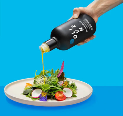 Extra Natives STAY SPICED ! Olivenöl wird aus der schwarzen Flasche über einen frischen Salat gegossen