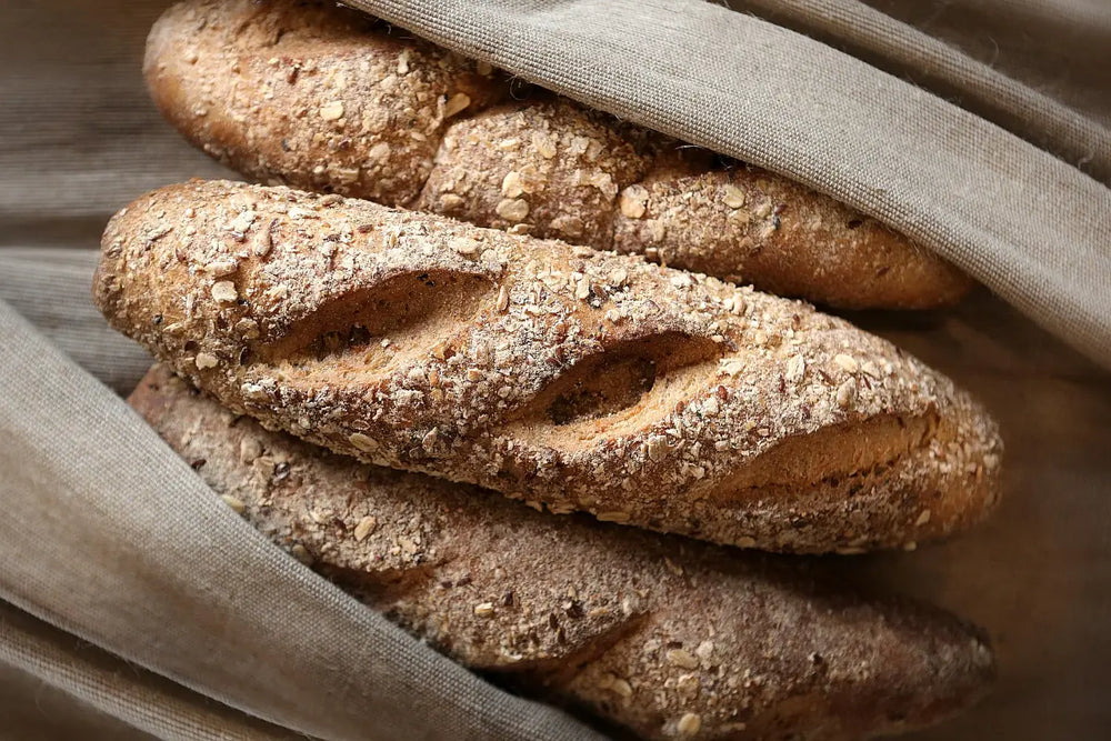 Frisch gebackene, rustikale Baguettes mit Körnern im Leinentuch verfeinert mit Premium Brotgewürzen online kaufen bei chefkoch-gewürze Schweiz