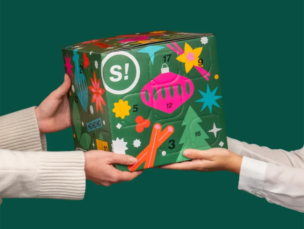 Zwei Hände übergeben den grünen STAY SPICED! Gewürz-Adventskalender 2026 in der Edition Spice Cube Pure von Chefkoch-Gewürze