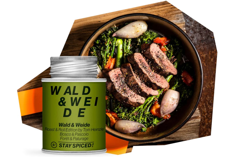 Eine Dose Wald & Weide Gewürz steht neben einem rustikal angerichteten Wildgericht mit rosa gebratenem dunklem Fleisch und Gemüse